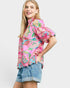 Woman wearing a colorful floral blouse and denim shorts on a white background
