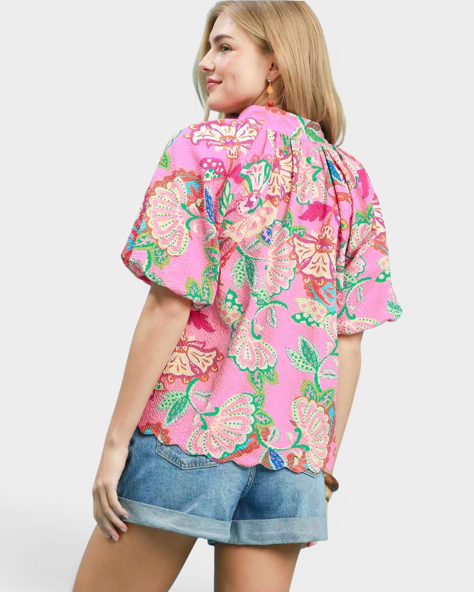 Woman wearing a pink floral kimono-style top on a plain background
