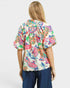 Woman wearing a colorful floral blouse with navy pants on a white background