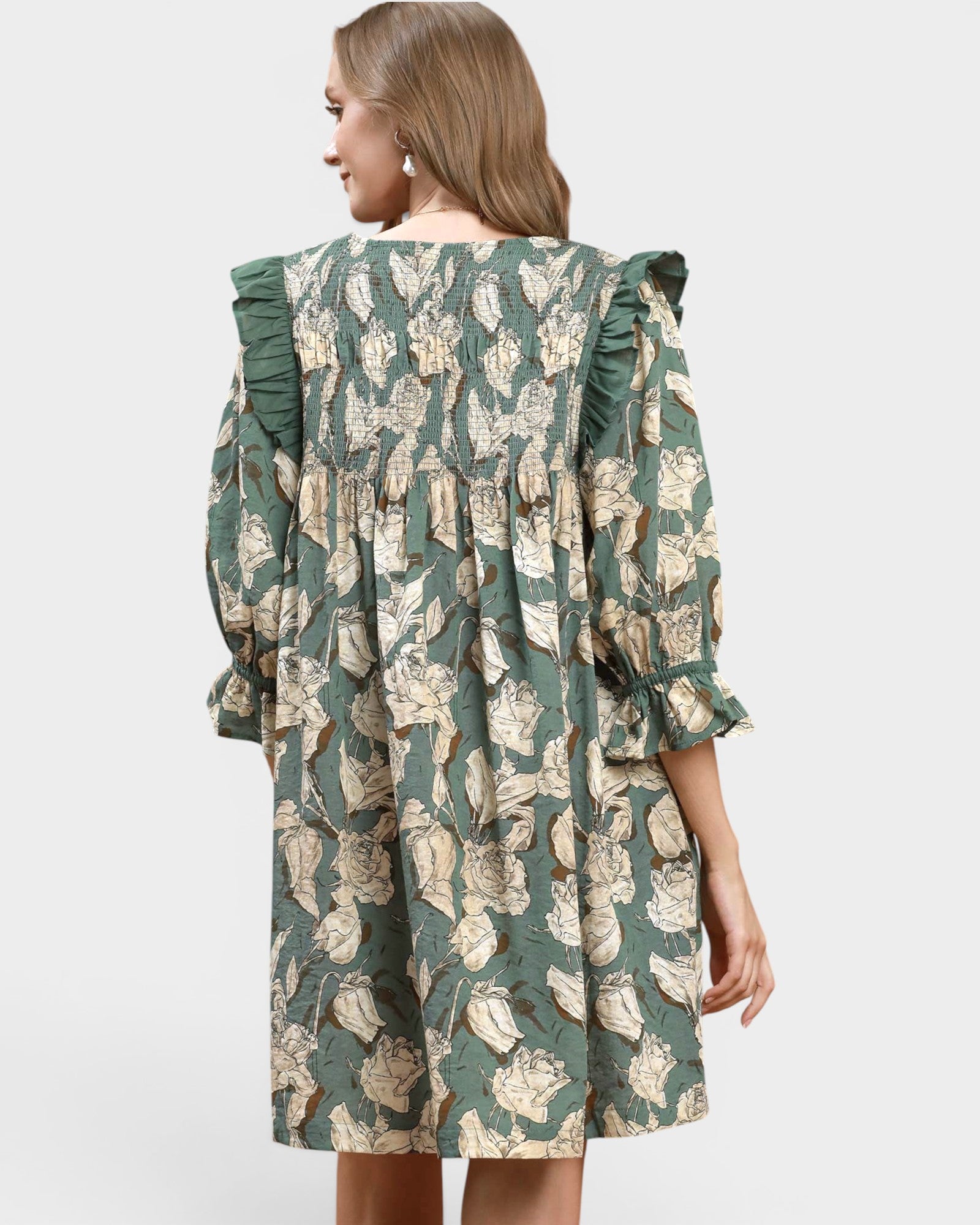 Woman wearing a green floral dress on a light gray background