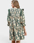 Woman wearing a green floral dress on a light gray background