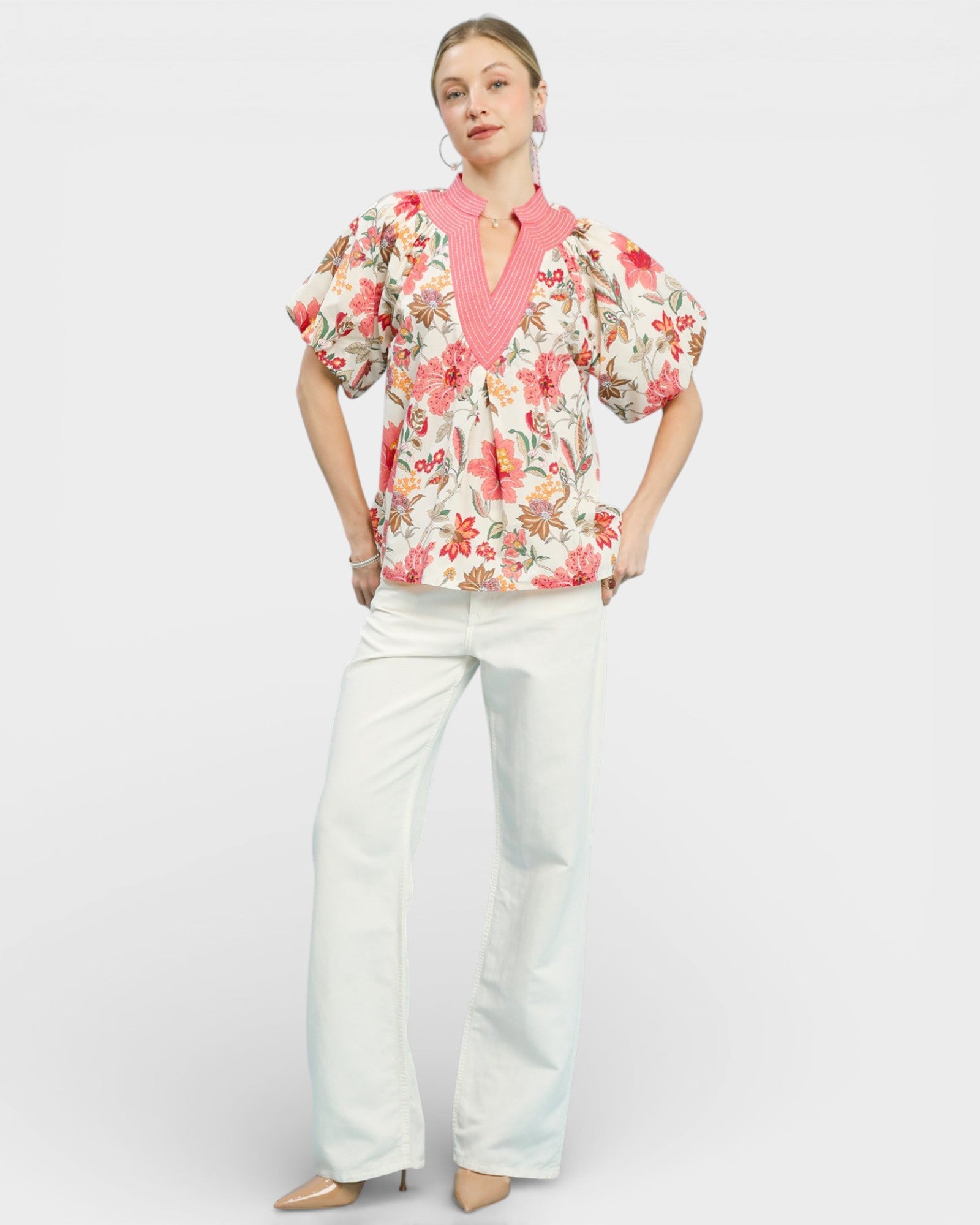 Woman wearing a floral blouse and white pants on a white background