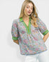 Woman wearing a floral blouse with green accents on a white background
