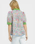 Woman wearing a floral blouse with green accents on a white background