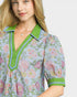 Woman wearing a floral blouse with green accents on a plain background
