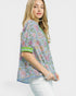 Woman wearing a floral patterned blouse with green accents on a white background