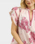 Woman wearing a floral dress with pink flowers on a white background