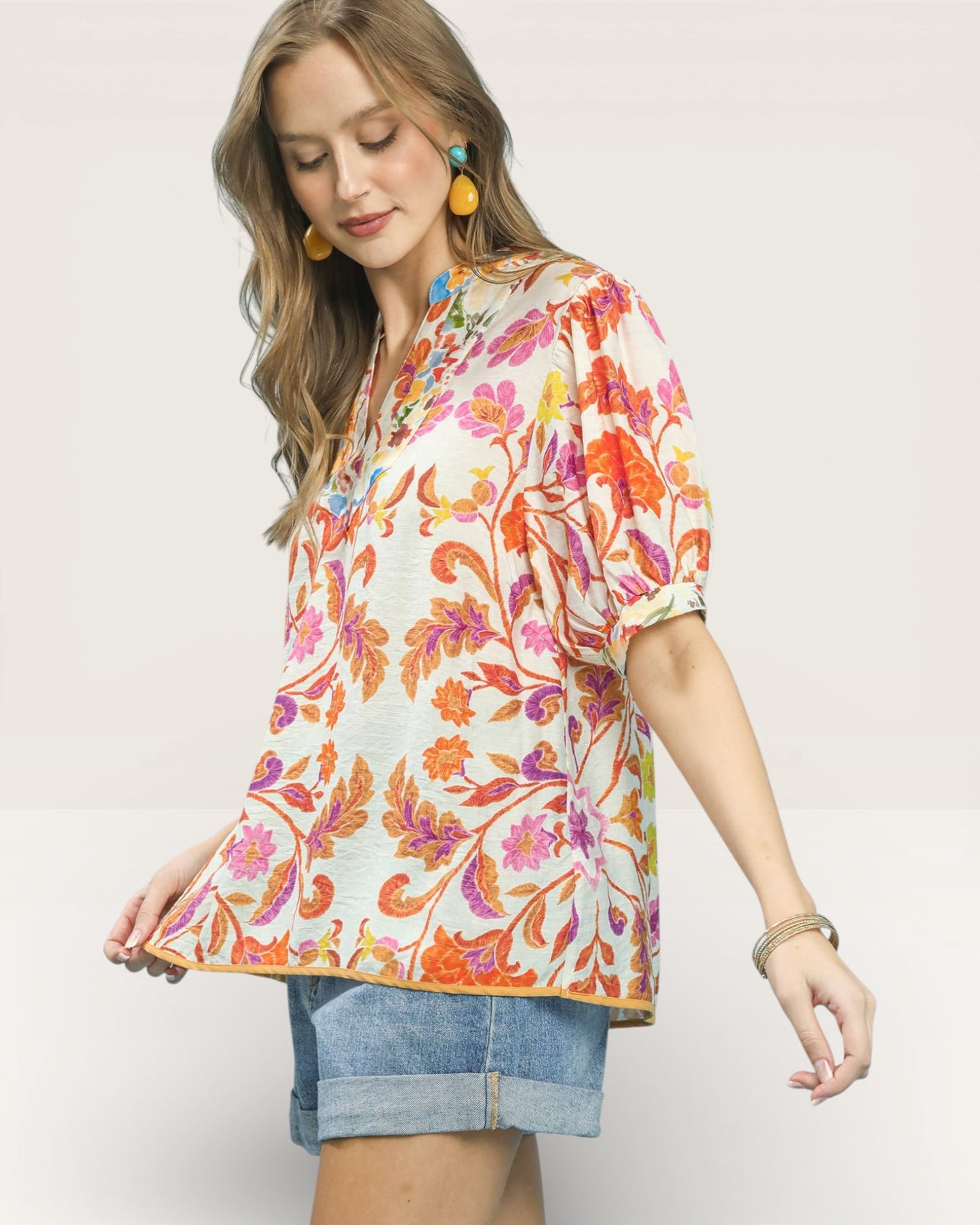 Woman wearing a colorful floral blouse with a plain background