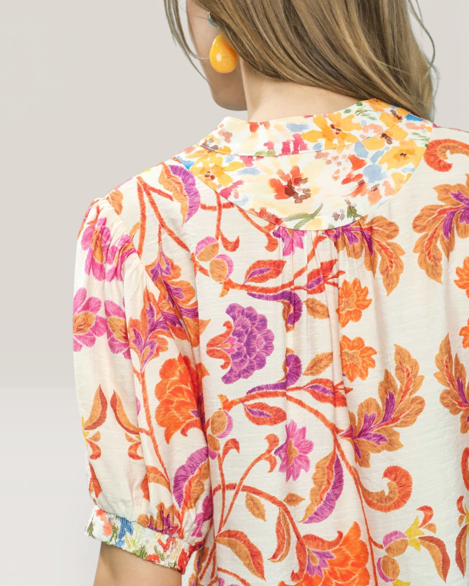 Woman wearing a colorful floral blouse against a plain background
