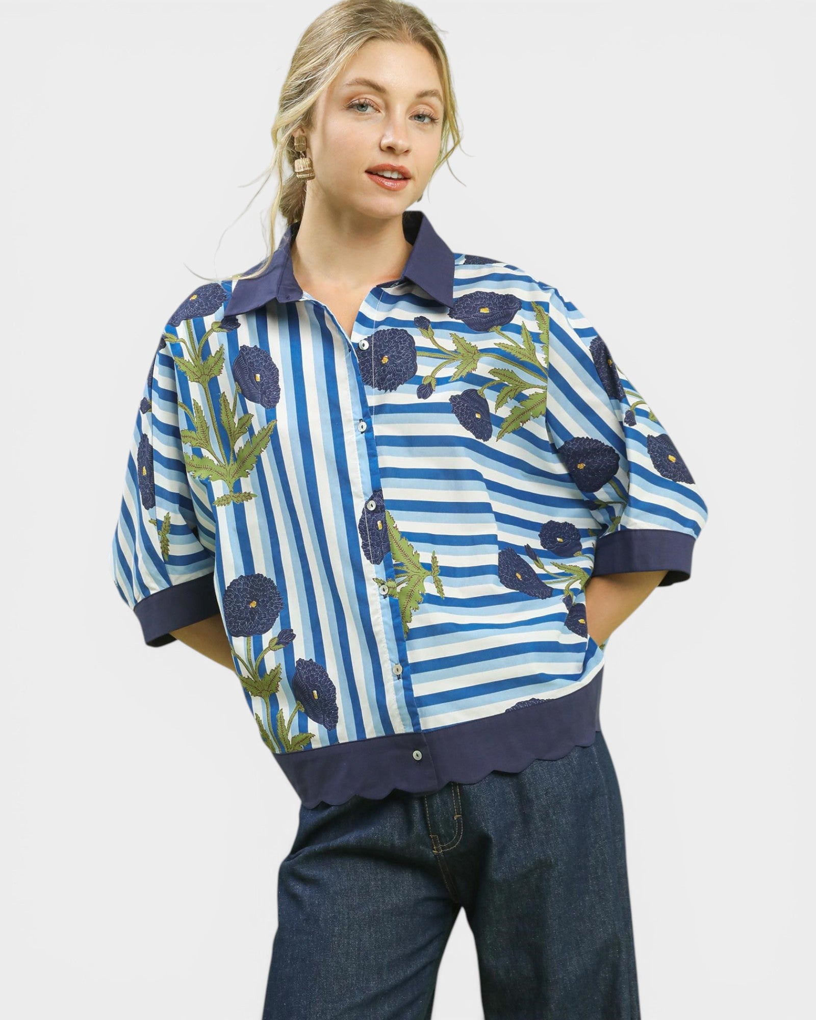 Woman wearing a blue and white striped shirt with floral patterns on a plain background