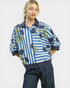 Woman wearing a blue and white striped shirt with floral patterns on a plain background