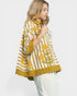 Woman wearing a yellow and white patterned blouse on a white background