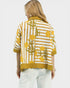 Woman wearing a yellow and white patterned shirt on a white background