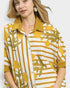 Woman wearing a yellow and white patterned shirt with a plain background
