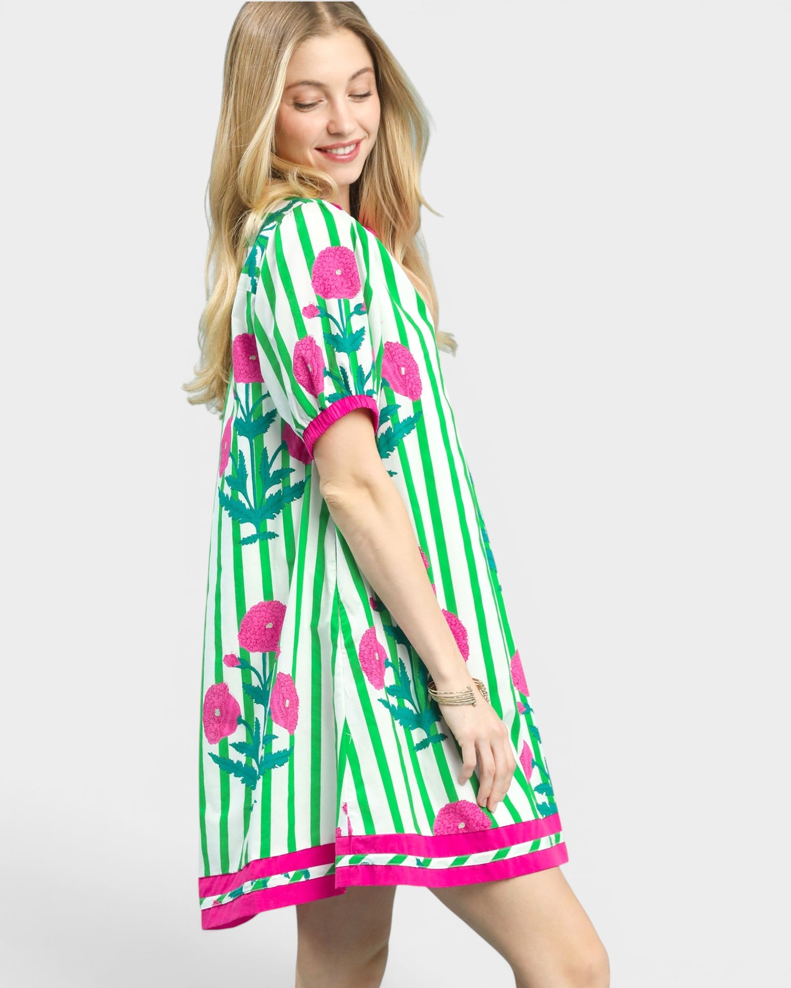 Woman wearing a green dress with pink floral patterns on a white background