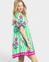 Woman wearing a green dress with pink floral patterns on a white background