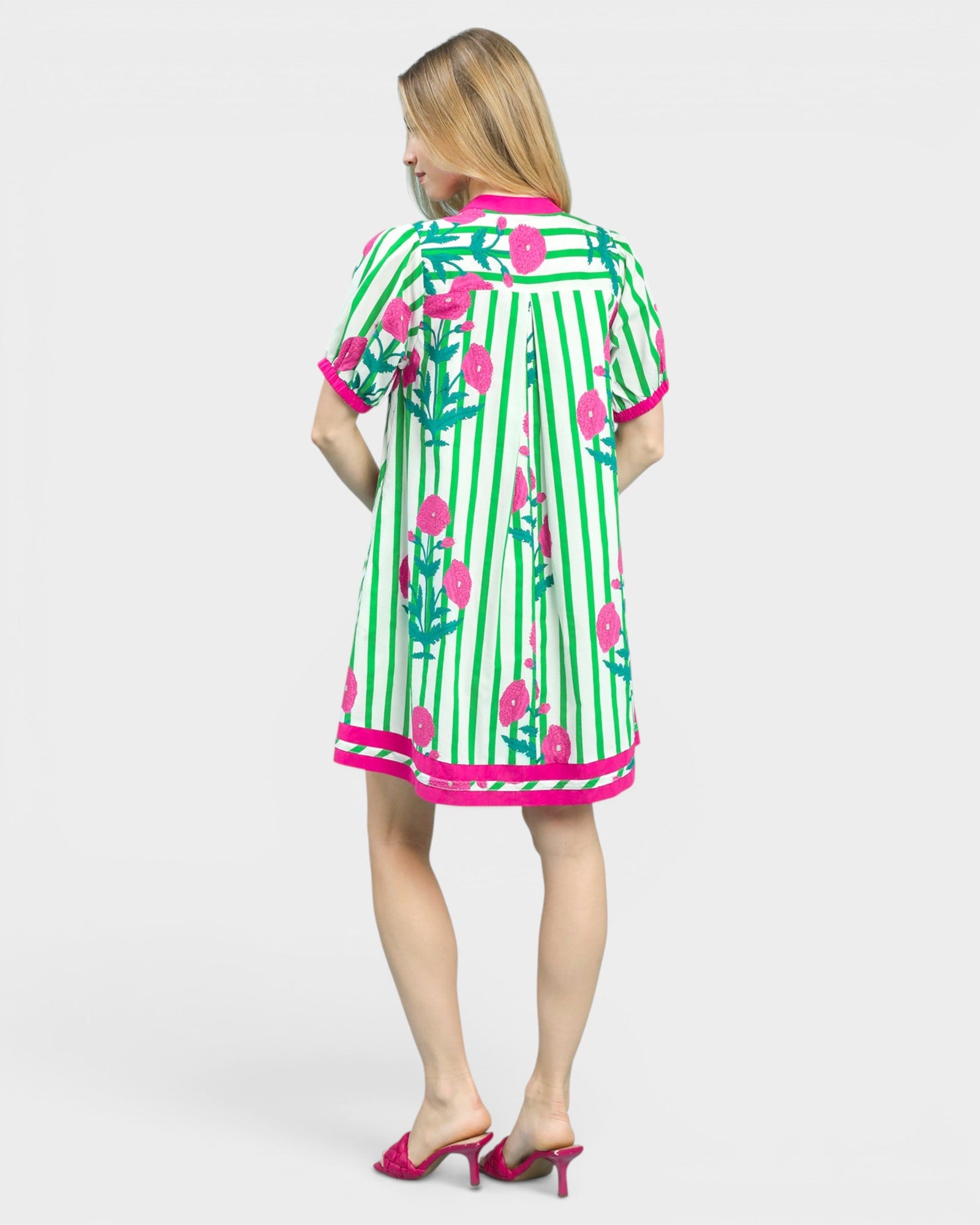 Woman wearing a green and pink dress with floral patterns on a white background