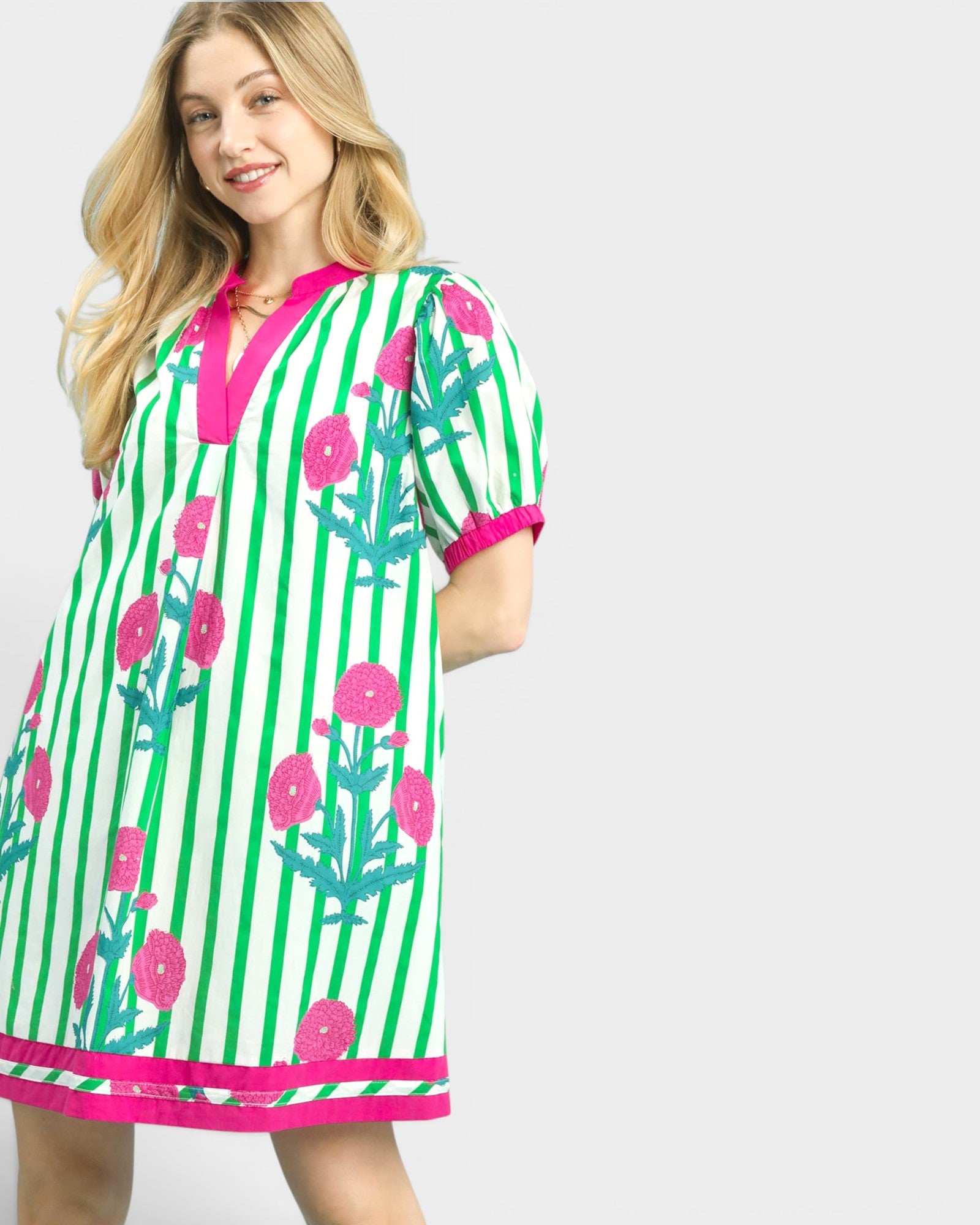 Woman wearing a green and pink floral dress with stripes on a white background
