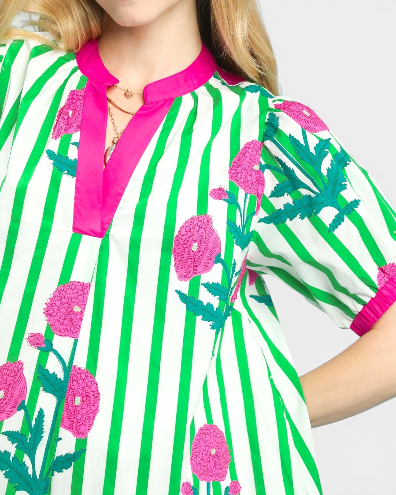 Close-up of a colorful dress with green stripes and pink floral patterns on a white background