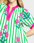 Close-up of a colorful dress with green stripes and pink floral patterns on a white background