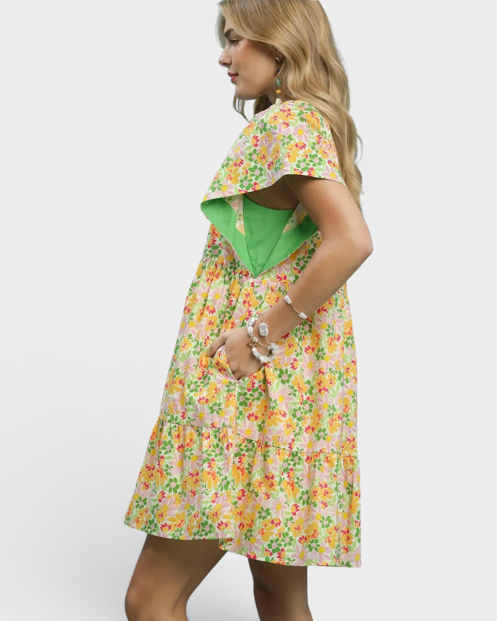 Woman wearing a floral dress with a green jacket on a white background