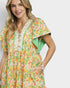 Woman wearing a colorful floral dress on a plain background