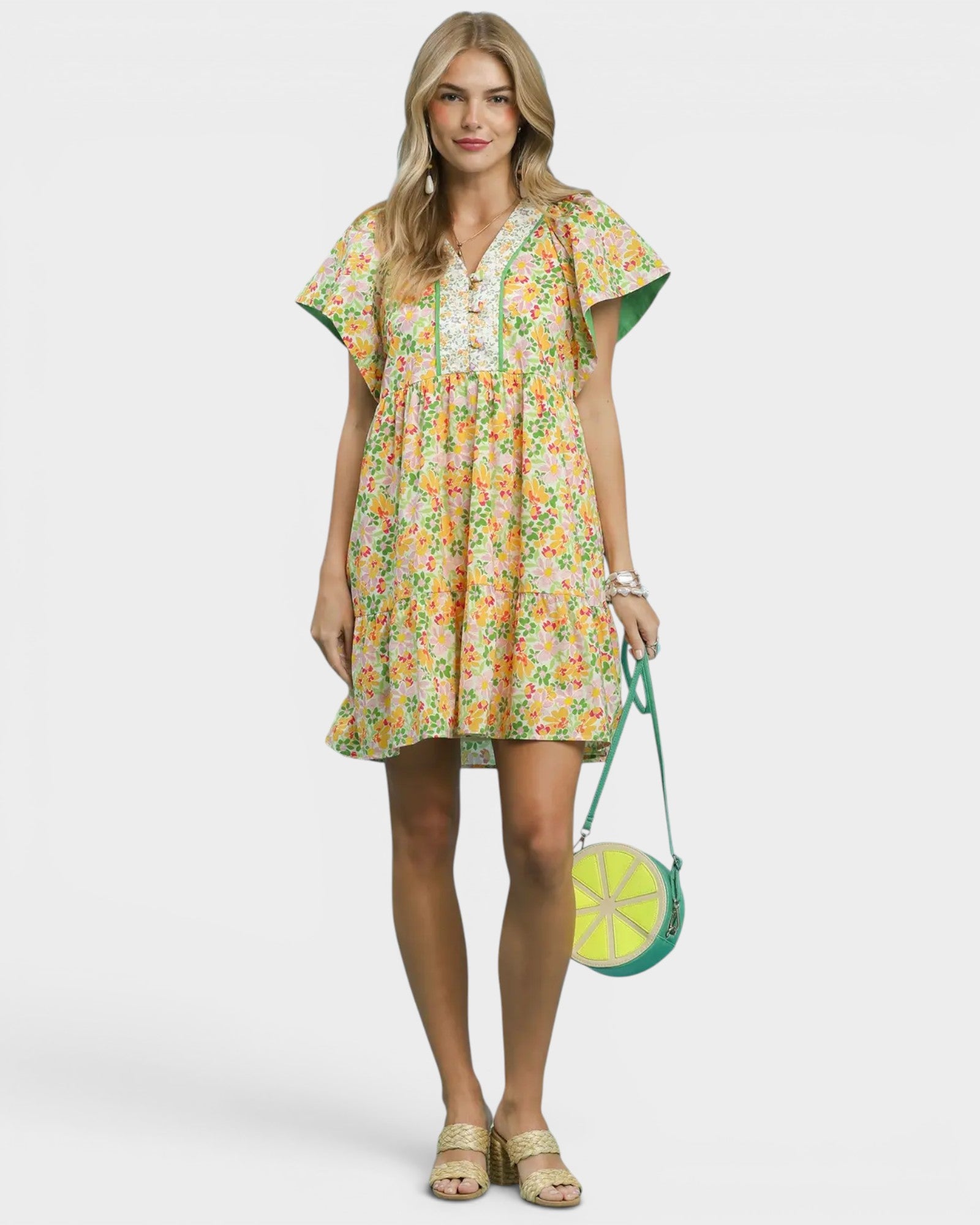 Woman wearing a floral dress holding a green handbag on a white background