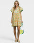 Woman wearing a floral dress holding a green handbag on a white background