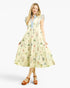 A woman modeling a tiered midi dress with a light cream base and a delicate multicolor floral print, featuring a light blue button-up collar and ruffled sleeves, paired with brown platform sandals against a light gray background.
