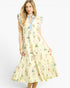 A woman modeling a sleeveless midi dress with a light yellow base, a blue collar, and a multicolor floral print, set against a plain white studio background.