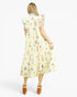 A woman shown from the back wearing a sleeveless midi dress with a light cream base and a delicate multicolor floral print. The dress features ruffled cap sleeves and a gathered waist.