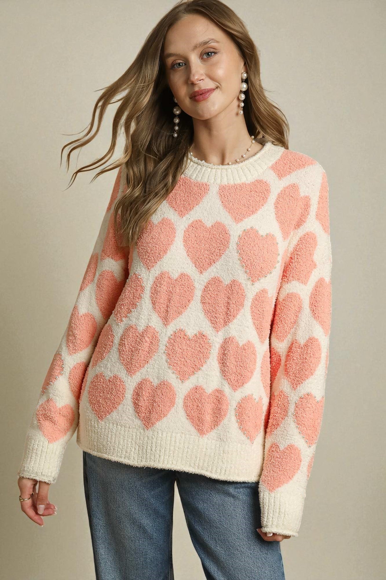 Woman wearing a sweater with pink heart pattern on a beige background