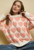 Woman wearing a cream sweater with pink heart patterns against a beige background