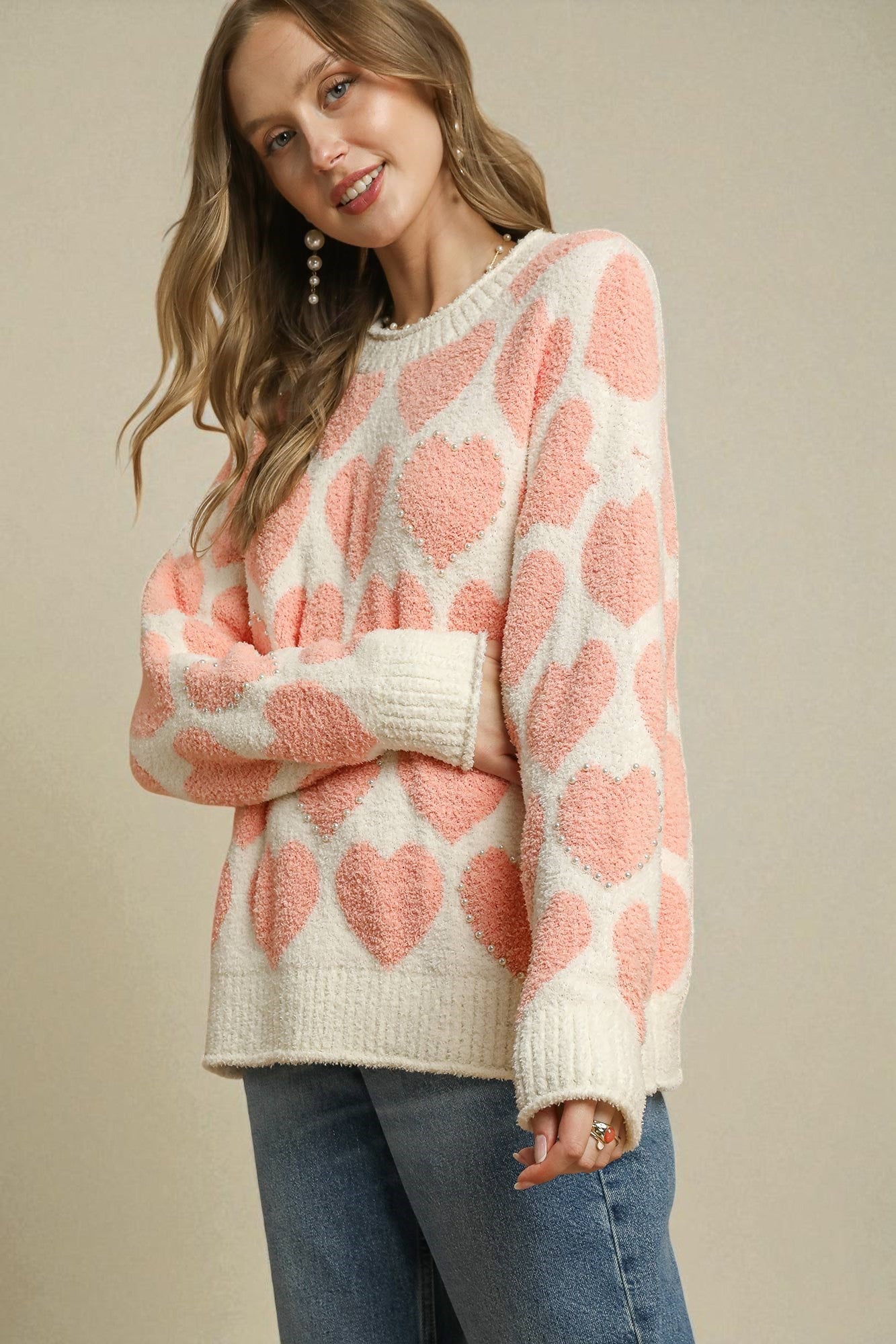 Woman wearing a pink and white patterned sweater against a beige background