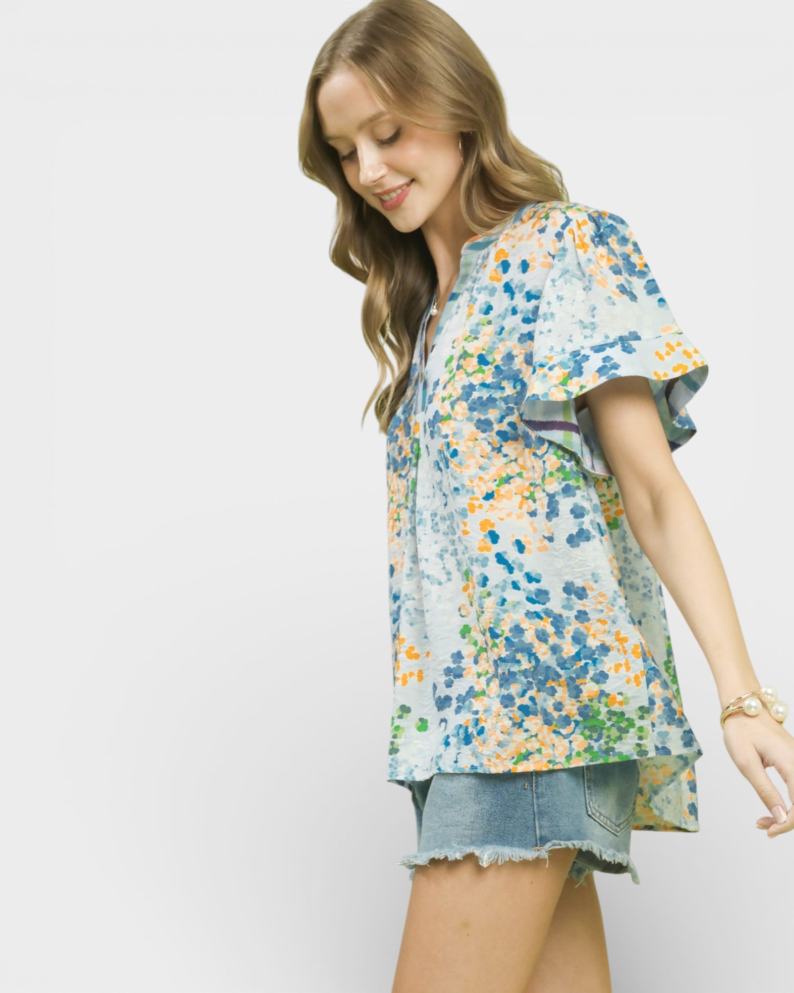 Woman wearing a floral blouse and denim shorts on a white background