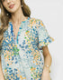 Woman wearing a colorful floral dress against a plain background