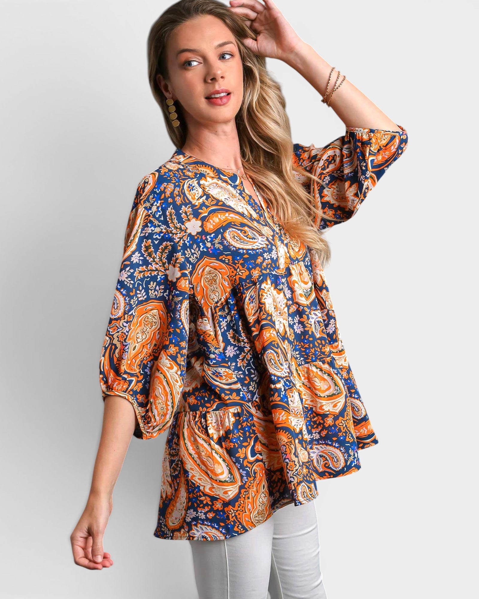 Woman wearing a colorful patterned blouse against a plain background