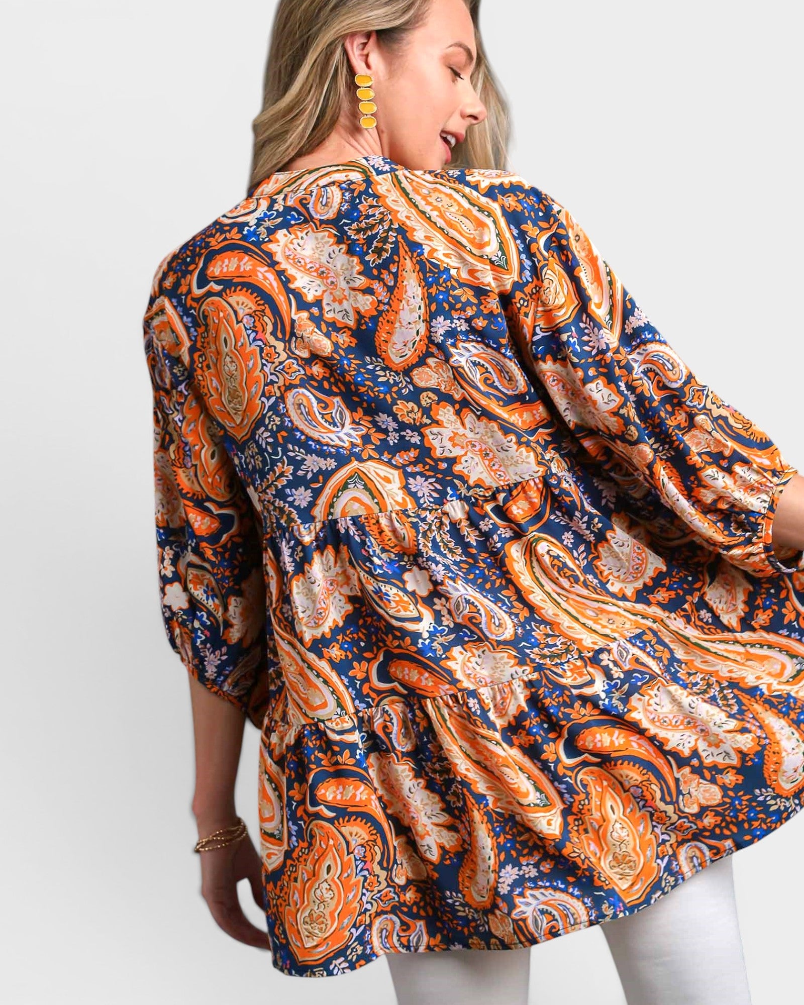 Woman wearing a patterned shirt with orange and blue design on a white background
