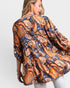 Woman wearing a patterned shirt with orange and blue design on a white background