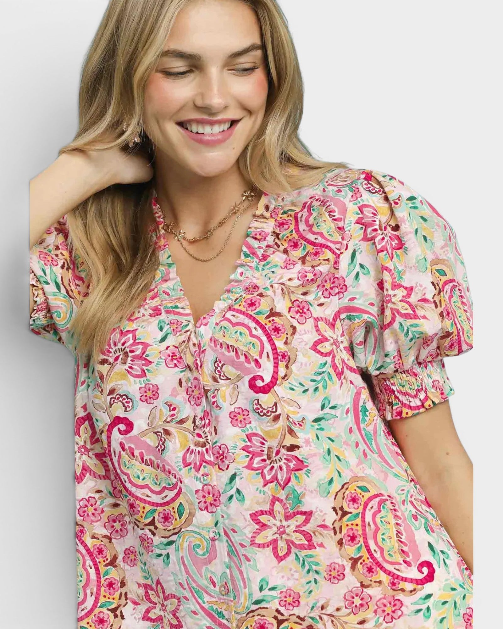 Woman wearing a colorful floral dress with puff sleeves on a plain background