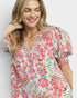 Woman wearing a colorful floral dress with puff sleeves on a plain background