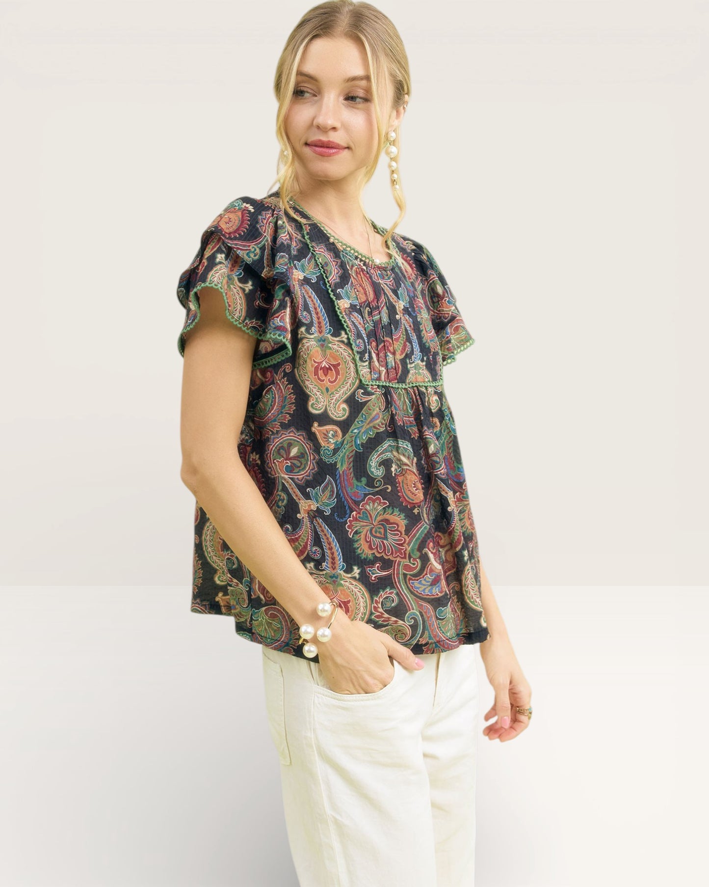 Woman wearing a patterned blouse with ruffled sleeves on a white background