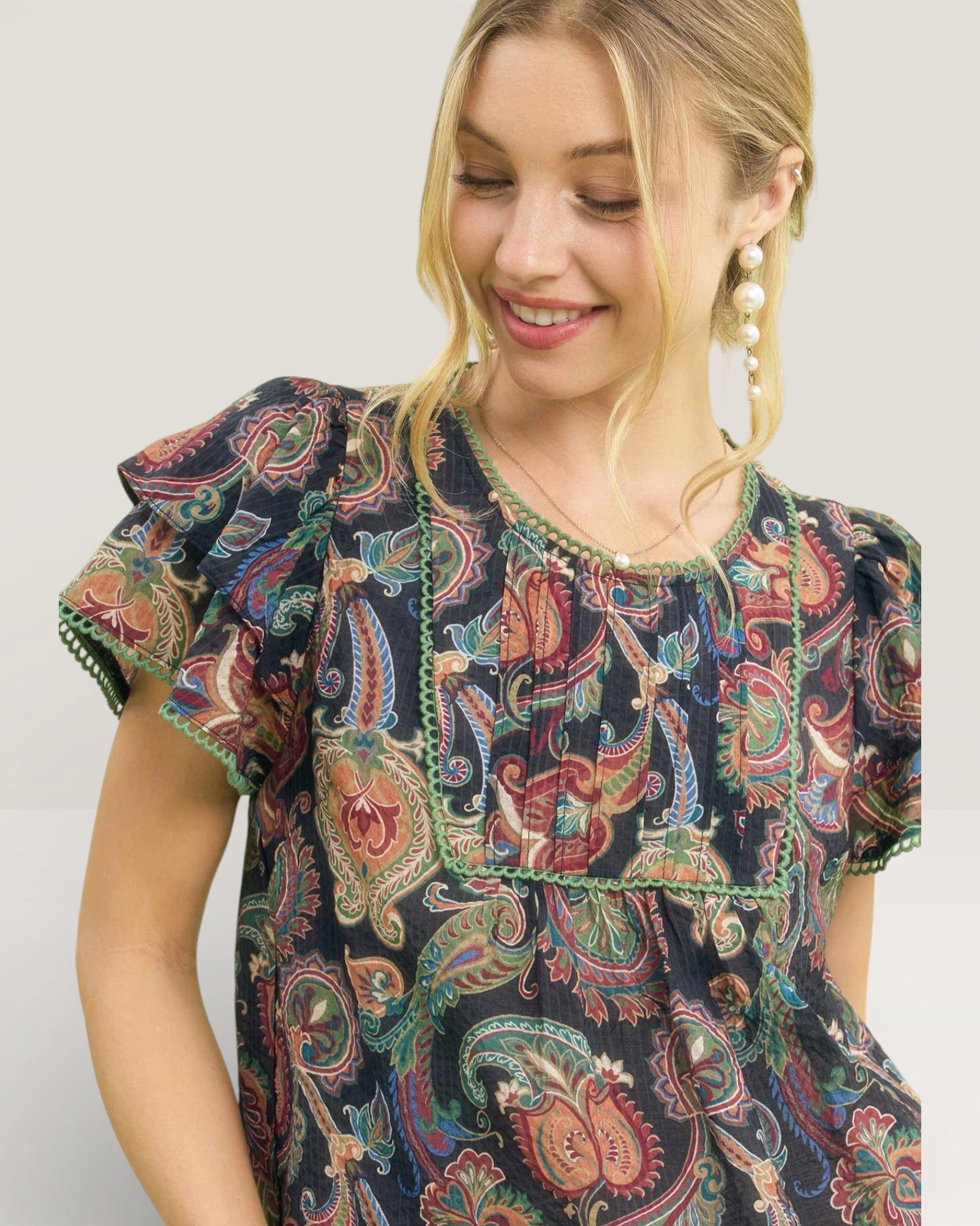 Woman wearing a patterned dress with ruffled sleeves on a plain background