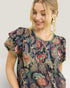 Woman wearing a patterned dress with ruffled sleeves on a plain background