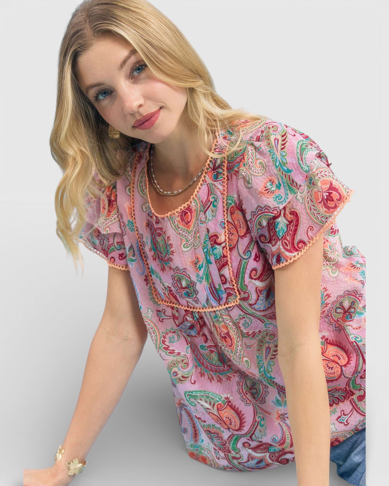 Woman wearing a pink paisley patterned top on a white background