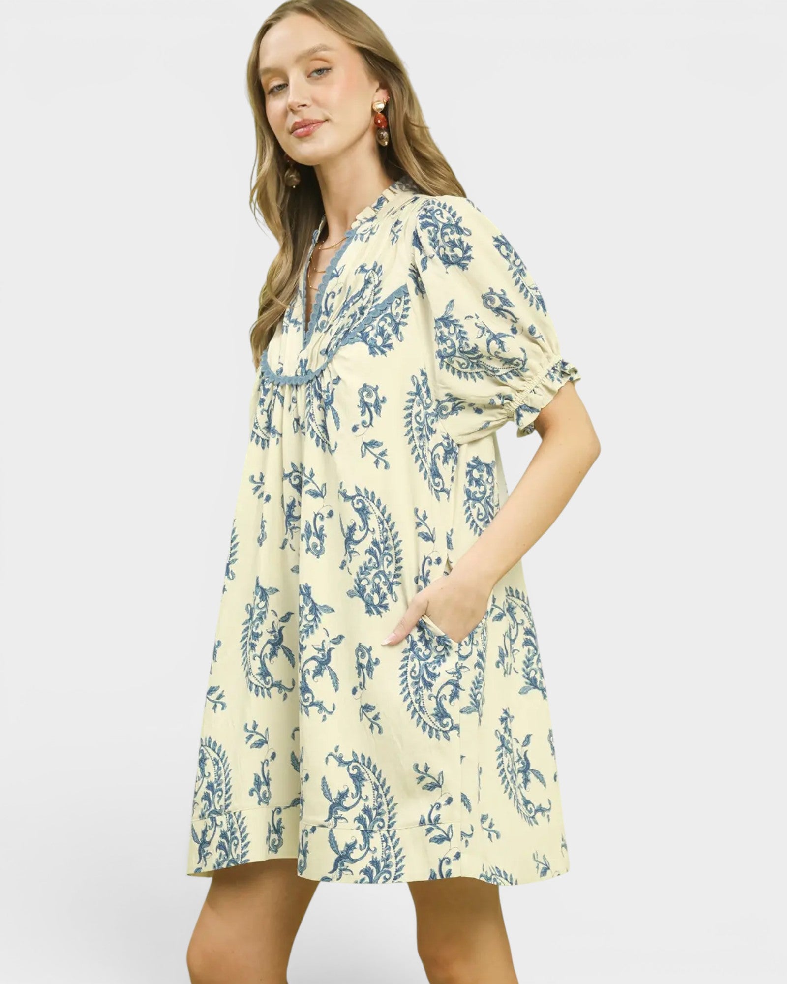 Woman wearing a yellow dress with blue floral pattern on a white background