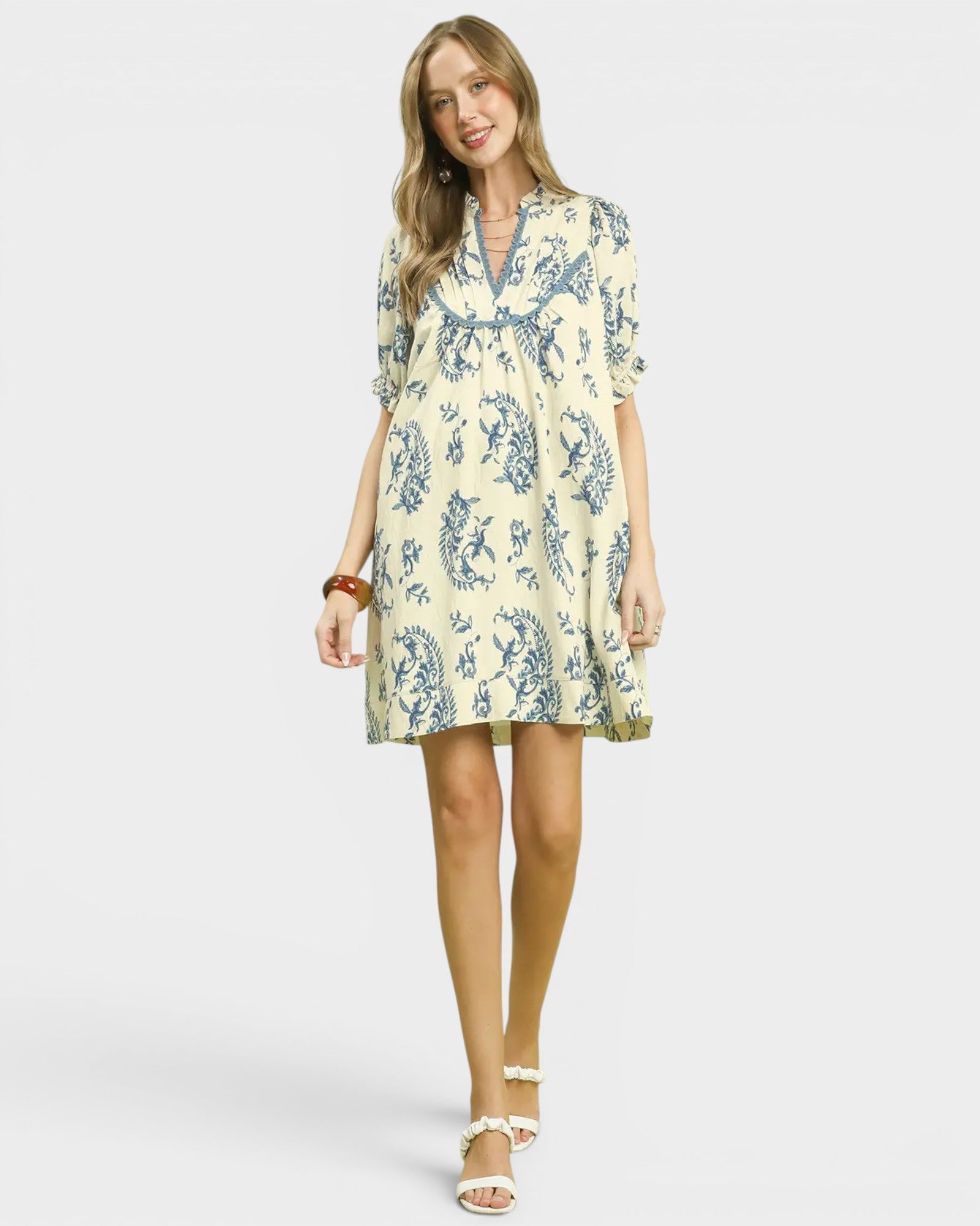 Woman wearing a yellow dress with blue floral pattern on a white background