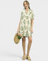 Woman wearing a floral dress holding a straw bag on a white background