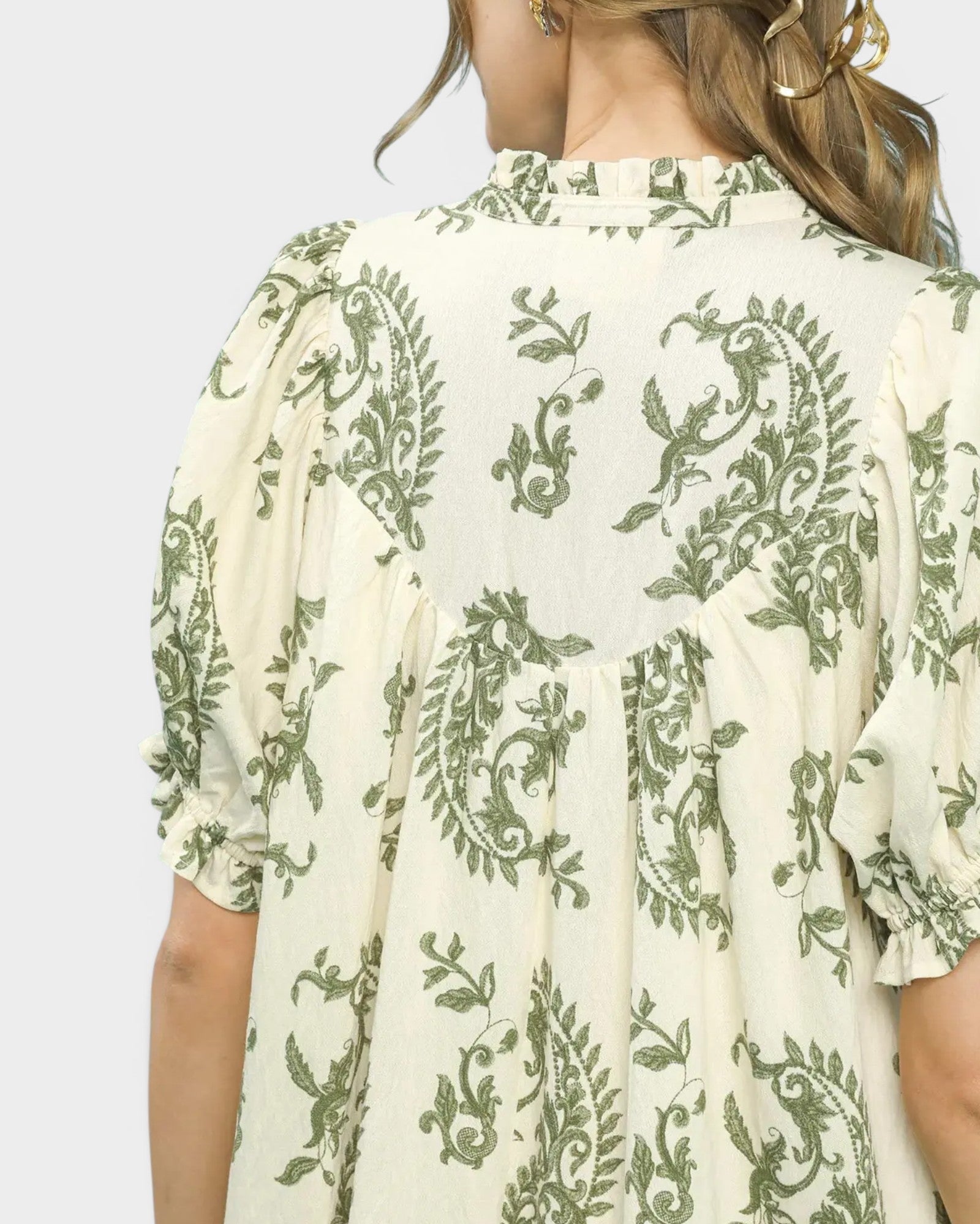 Green and white floral patterned dress on a plain background