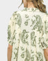 Green and white floral patterned dress on a plain background